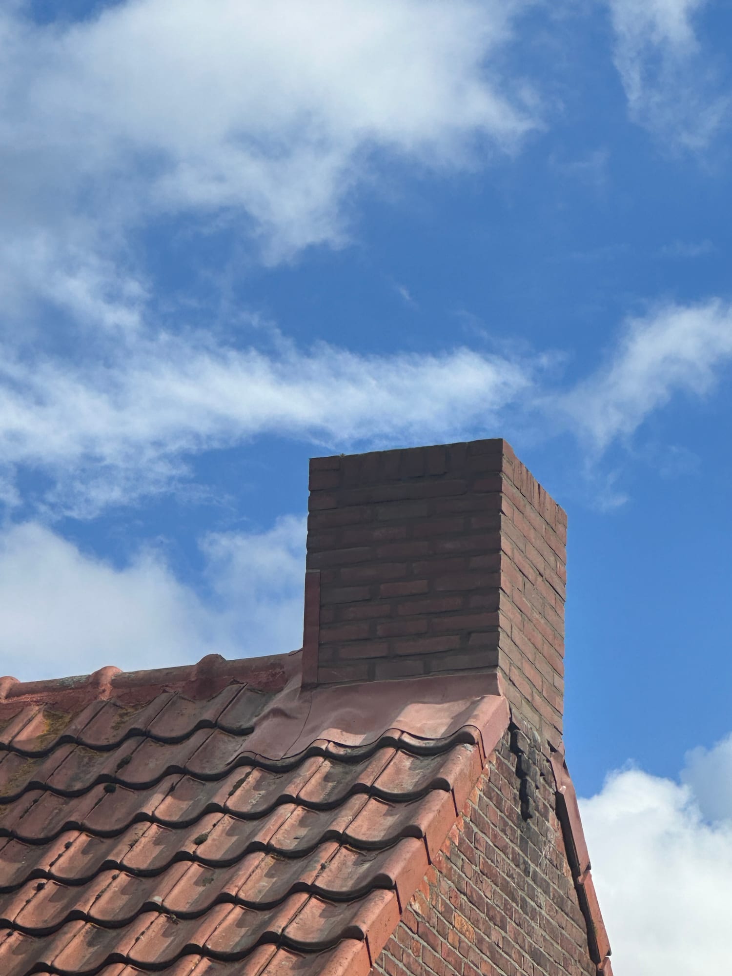 Gemetselde schoorsteen tegen een blauwe lucht, eigen werk